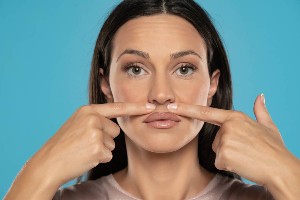 woman touches her face under her nose on a blue studio background